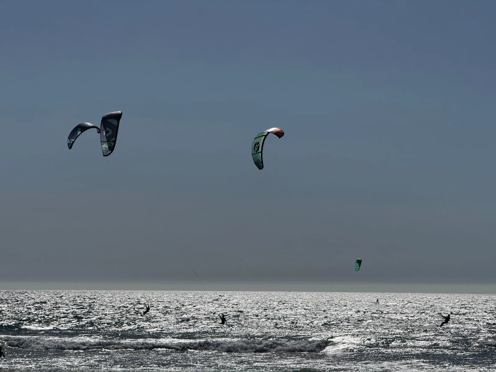 Kitesurfers and colourful kites above the Atlantic horizon